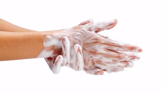 Close-up of two hands covered in soap lather against a white background